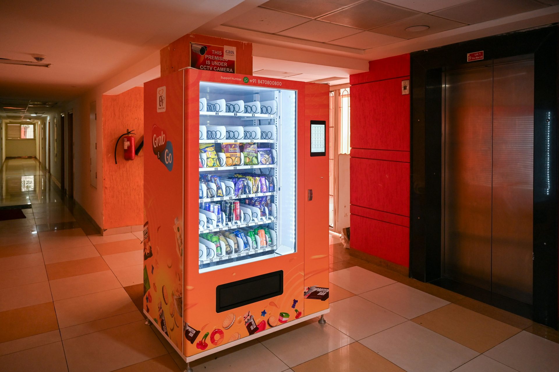 A vending machine stands in a building's corridor.